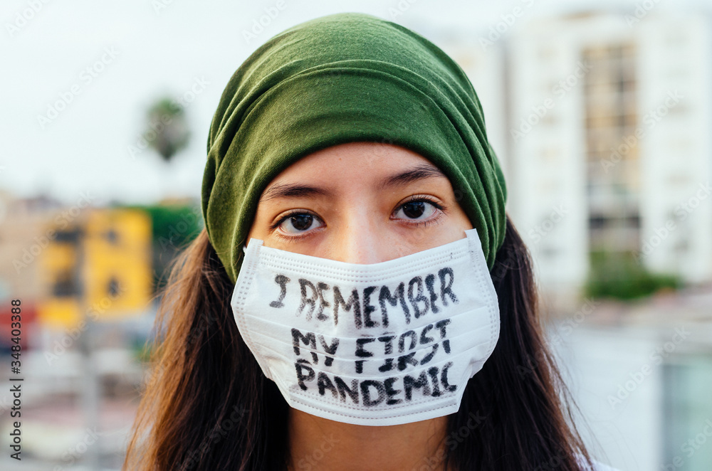Young woman in protective sterile medical mask on her face looking at the camera outdoors, in the Young woman in protective sterile medical mask on her face looking at the camera outdoors, in the