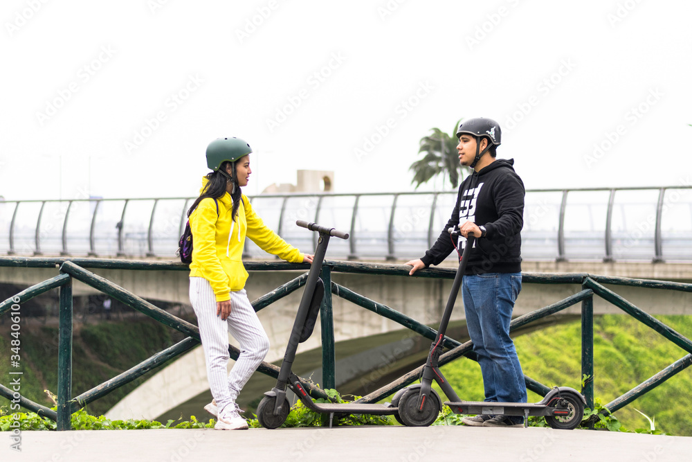 Two smiling friends showing helmet, concept in driving safety with a means of transportation Two smiling friends showing helmet, concept in driving safety with a means of transportation