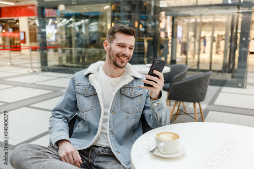 positive guy sitting at a table and looking at the phone