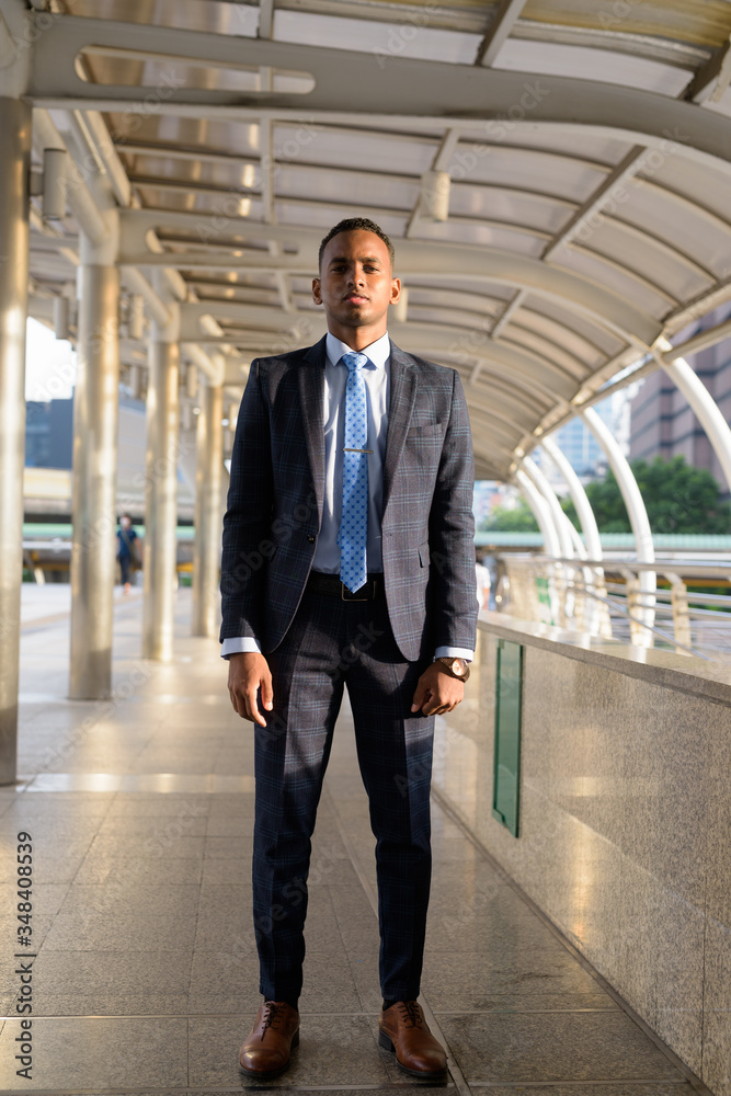Full body shot of young handsome African businessman wearing suit in the city