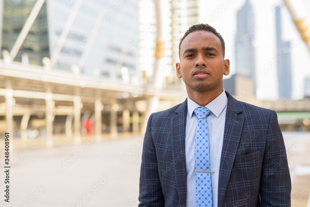 Young handsome African businessman wearing suit in the city