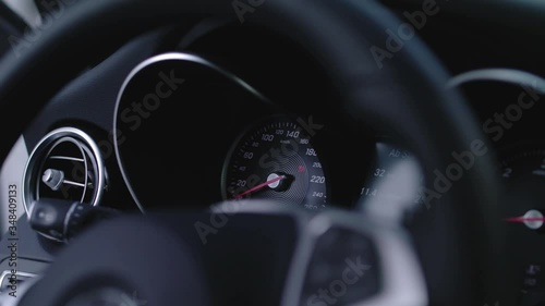 Detail shot of a speedometer in a car with black interieur going from zero to full speed when the car is turned on. photo
