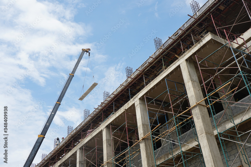 Crane is lifting a prestressed floor to installation building. And scaffold for supporting the building structures on the construction site. 