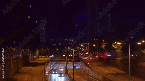 Driving cars in Munich, bavaria. A timelapse of the night traffic in central munich with many cars driving by, view from a bridge with famous architecture in the dark background. photo