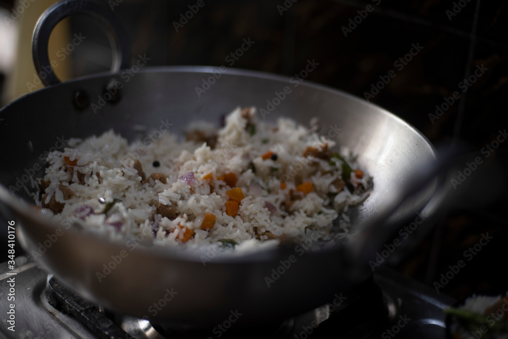Steamed rice with vegetables being cooked in a large pot in an Indian kitchen. Indian food and cooking.