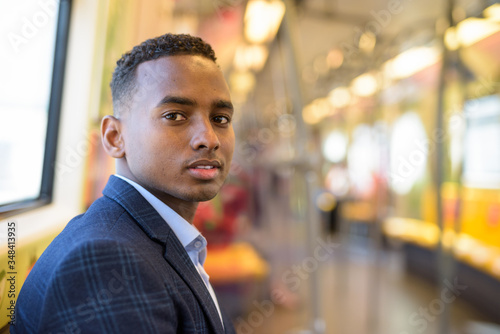Face of young handsome African businessman sitting inside the train