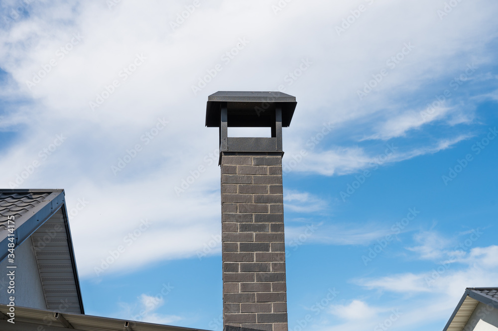 Obraz premium modern brick chimney pipe against a blue sky