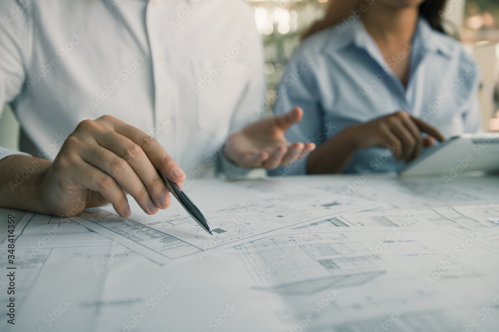 Architects engineer working with blueprints on table and discussing project together at the meeting in the office. Architects engineer working with blueprints on table and discussing project together at the meeting in the office.
