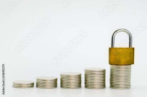 Closeup of stack of coins and golden master key on top of stack and white background with copy space for text.