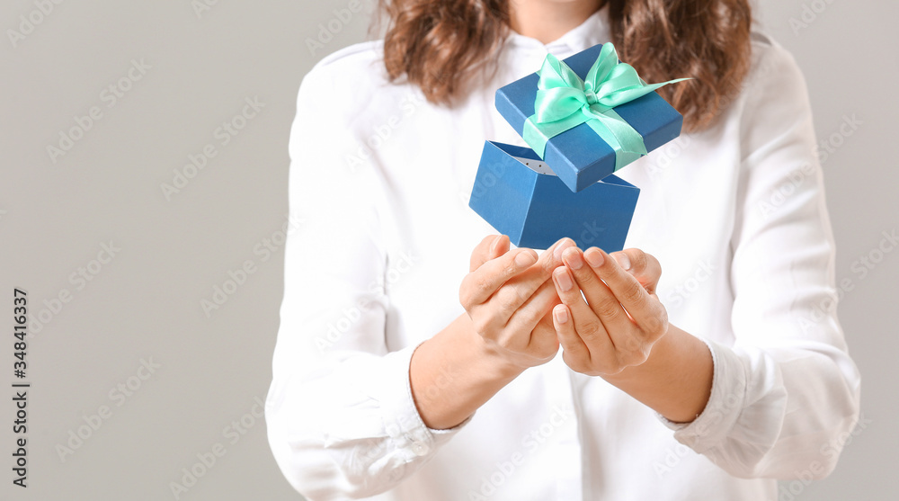 Young woman with gift on light background Young woman with gift on light background