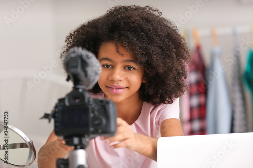 African-American teenage blogger adjusting camera for recording video at home