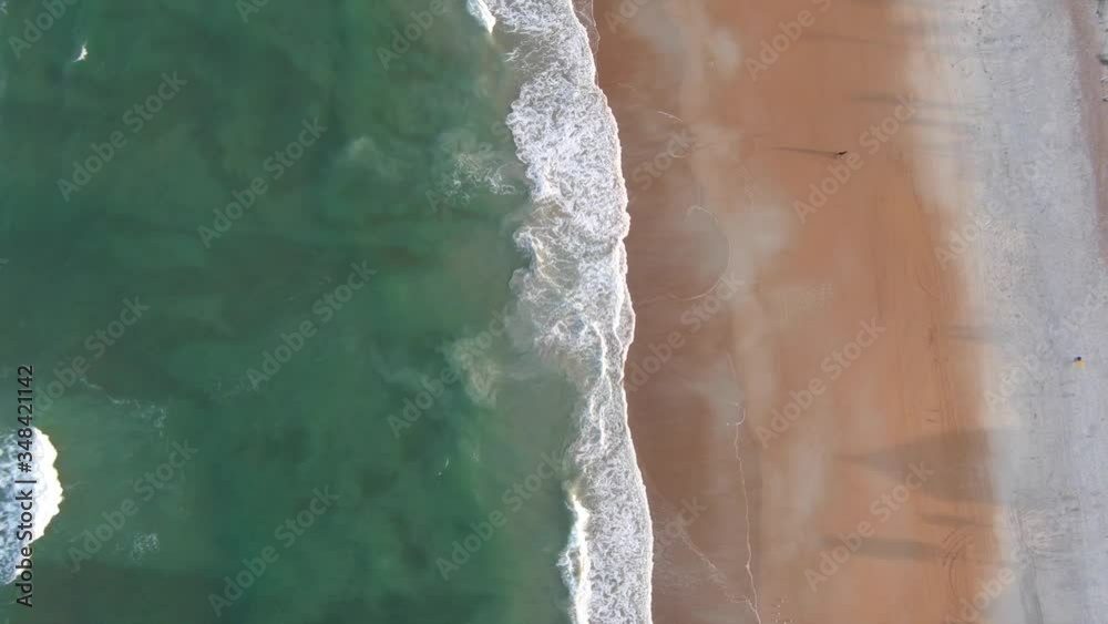 Aerial view of ocean meeting shoreline as waves crash at sunset. Aerial view of ocean meeting shoreline as waves crash at sunset.