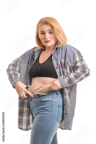 Sad overweight woman with scissors on white background. Weight loss concept