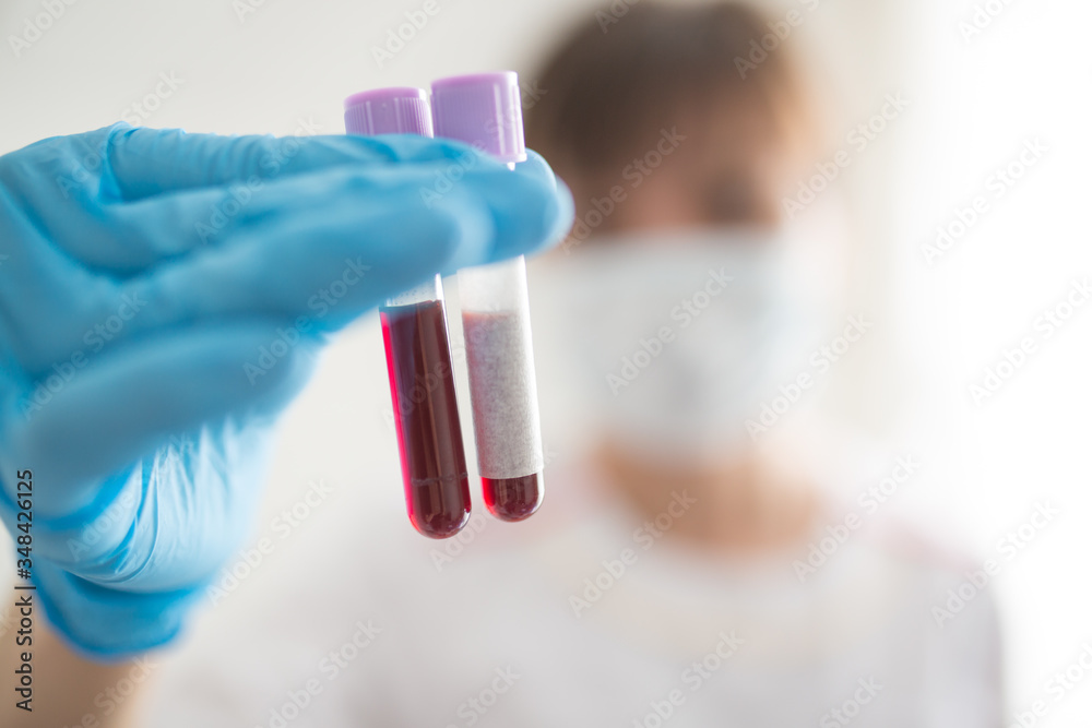 Female nurse holding test tube with blood sample and test tube with blank label Female nurse holding test tube with blood sample and test tube with blank label