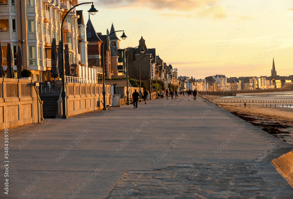 Obraz premium Beach in the evening sun and buildings along the seafront promenade in Saint Malo. Brittany, France