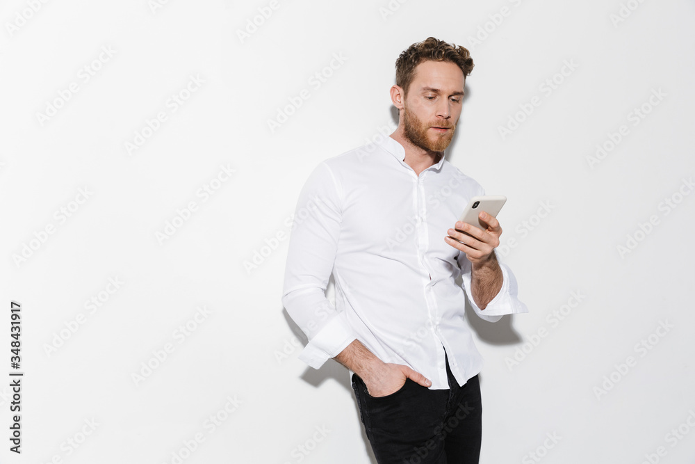 Image of handsome focused man in shirt posing and using cellphone Image of handsome focused man in shirt posing and using cellphone