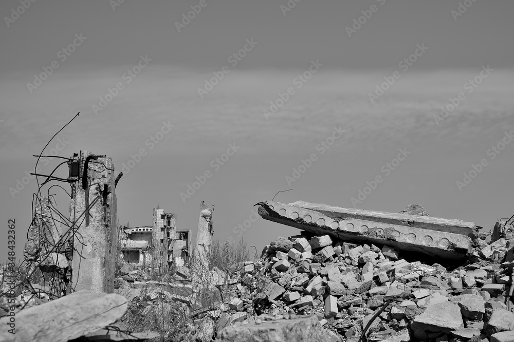 Fototapeta premium The remains of a destroyed building with concrete Foundation piles sticking out of the ground. Black and white background