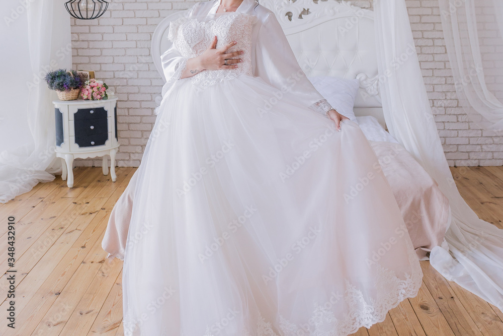 the bride in a peignoir holds a wedding dress the bride in a peignoir holds a wedding dress