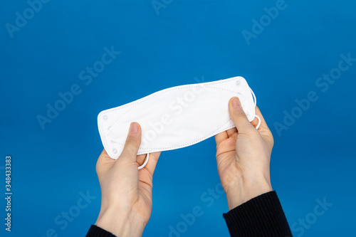 Holding a white surgical mask on blue screen