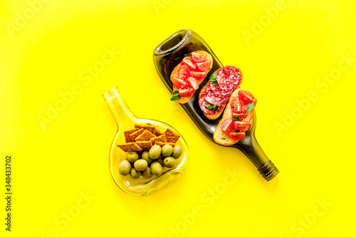 Snack set on wine bottles on yellow desk from above