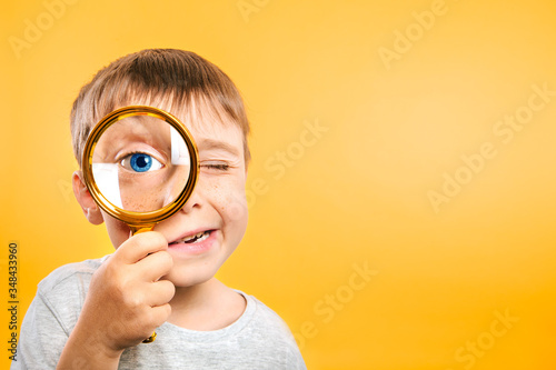 Child see through magnifying glass on the color yellow backgrounds. Big kid eye photo