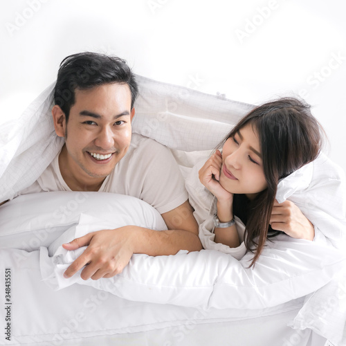 Happy Asian couple under blanket on bed together, lifestyle concept.