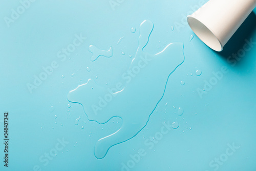 Foto Cup with spilled water on a blue background