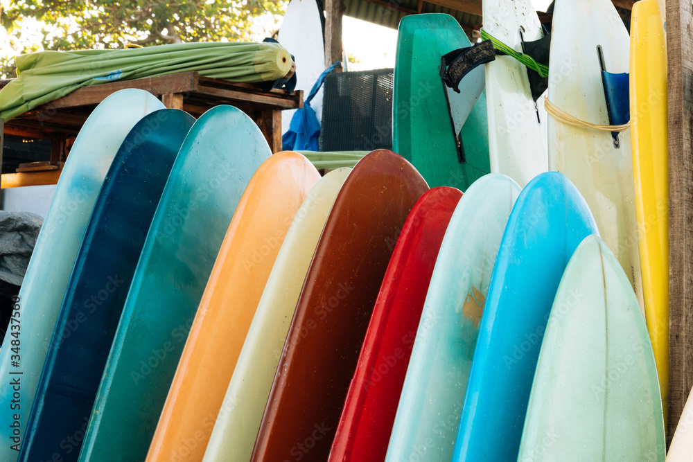 Foto Stock Set of colorful surfboard for rent on the beach. Multicolored  blue, red, white surf boards different sizes and colors surfing boards on  stand, surfboards rental place | Adobe Stock