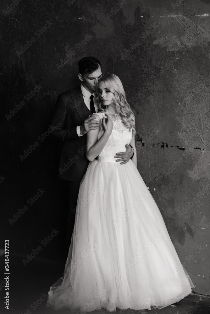Cute wedding couple in the interior of a classic studio decorated. They kiss and hug each other. Cute wedding couple in the interior of a classic studio decorated. They kiss and hug each other.