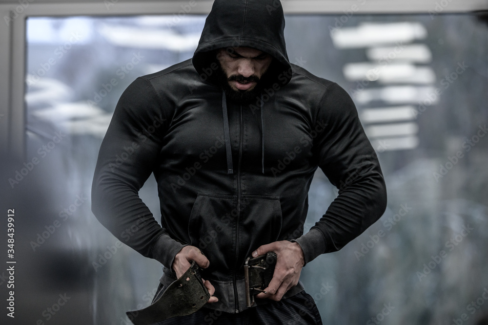 strong young bearded mighty man in hoodie wearing powerlifting belt for  heavy hardcore weight training workout indoors sport fitness gym foto de  Stock | Adobe Stock