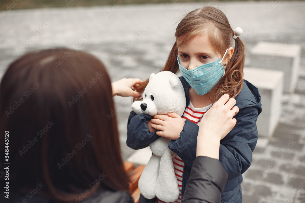 Woman in a disposable mask is teaching her child to wear a respirator. Woman in a disposable mask is teaching her child to wear a respirator.
