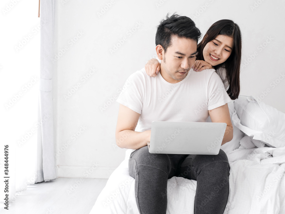 Happy Asian couple using laptop on bed together at home, lifestyle and work from home concept. Happy Asian couple using laptop on bed together at home, lifestyle and work from home concept.
