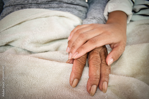 Close up granddaughter takes care of the health sick grandmother at home by holding hands. Lifestyle support the love of the family.