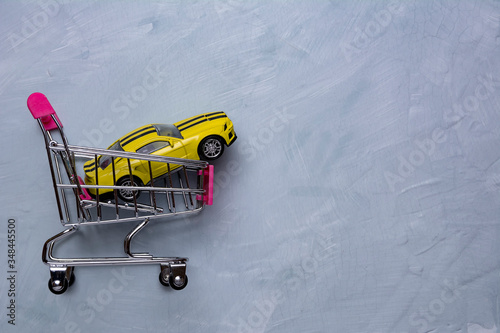 Shopping cart with yellow car. Car purchase concept. Concept trade in.