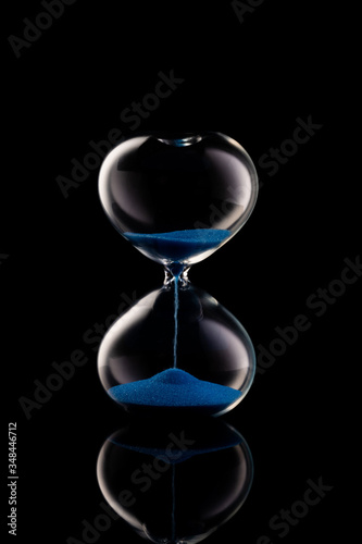 Blue sand hourglass on black background