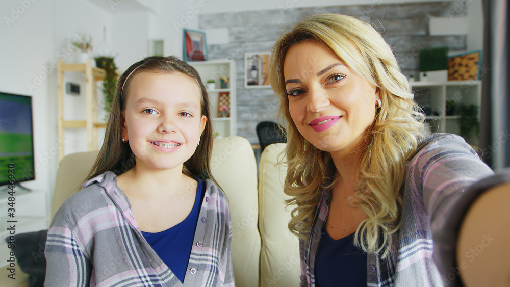 Pov of happy daughter with braces and her mother making funny faces in front of camera. Pov of happy daughter with braces and her mother making funny faces in front of camera.