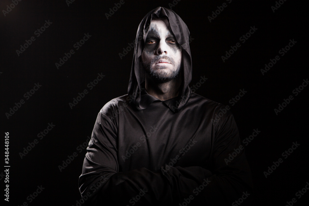 Fototapeta premium Thoughtful grim reaper over black background. Spooky monster.