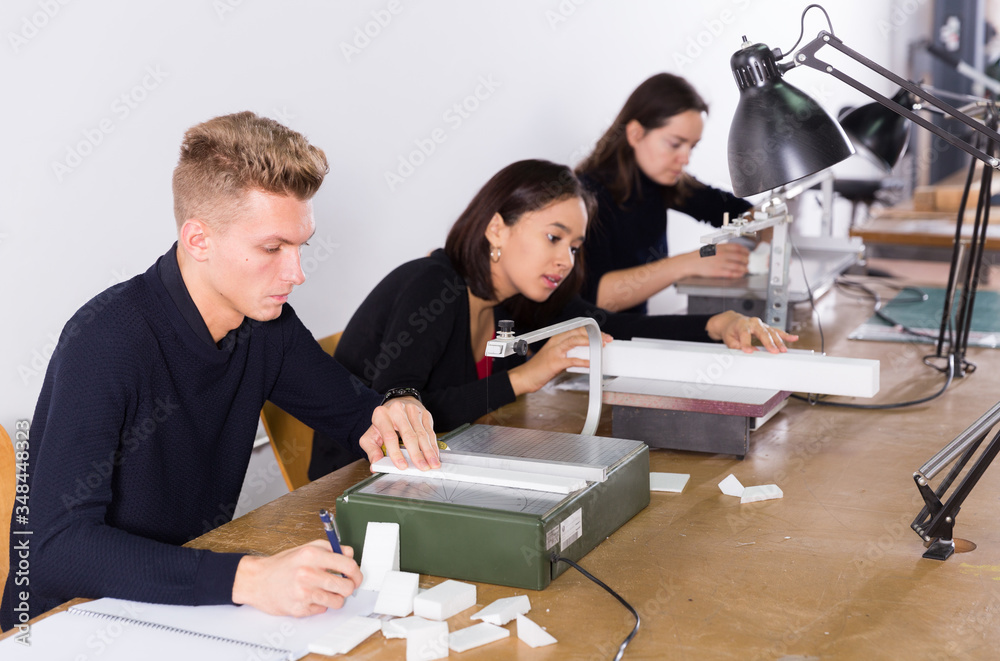 Obraz premium Student using scroll saw in architectural modeling