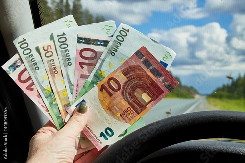 Euro banknotes of various denominations in a woman hand inside of a car