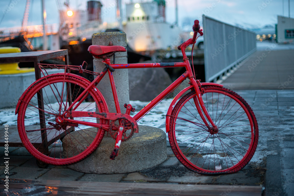 Ein rotes Fahrrad mit plattem Reifen lehnt an einem Poller in einem Hafen-Konzept Verlassen, Einsam