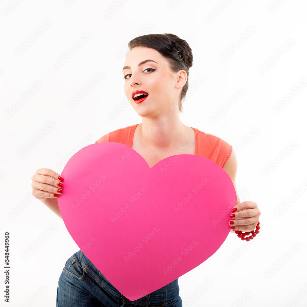 Pinup girl holding pink heart and happy smiling. Retro portrait of young cheerful woman in pin-up style, vintage stylization over white. Love symbol, St. Valentine Day, feeling concept Pinup girl holding pink heart and happy smiling. Retro portrait of young cheerful woman in pin-up style, vintage stylization over white. Love symbol, St. Valentine Day, feeling concept