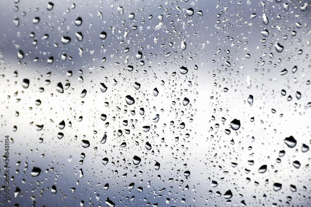 Drops of morning summer rain on the transparent window of the house on a blurred background of nature. Summer vacation and travel concept Drops of morning summer rain on the transparent window of the house on a blurred background of nature. Summer vacation and travel concept