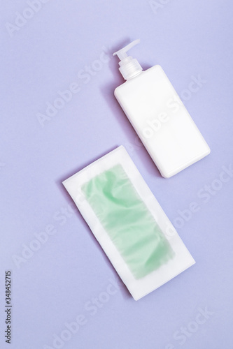 Set of female of hair removal. Wax strips, body moisturizer on blue paper background with copy space. Top view.