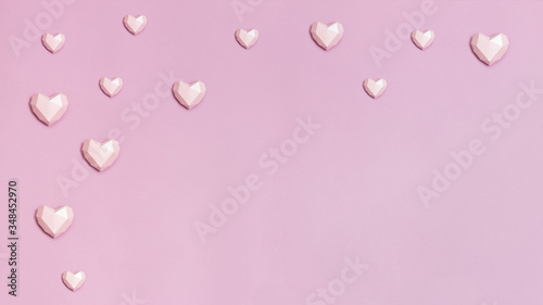 Banner with pink polygonal paper hearts on pink paper. Holiday background with copy space for Valentines Day. Love concept. Plain colored. Monochrome image. Minimal style.