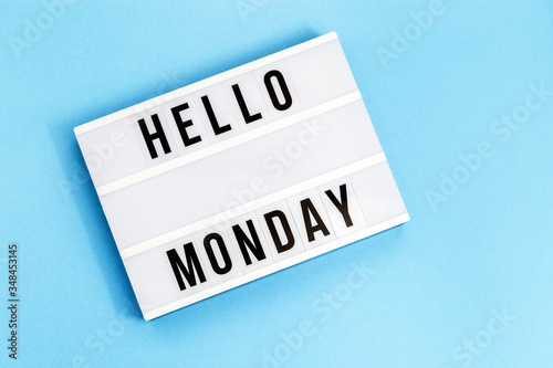 Text "hello monday" on lightbox for holiday - Thank God It’s Monday. Start of working week concept. Top view on blue background.