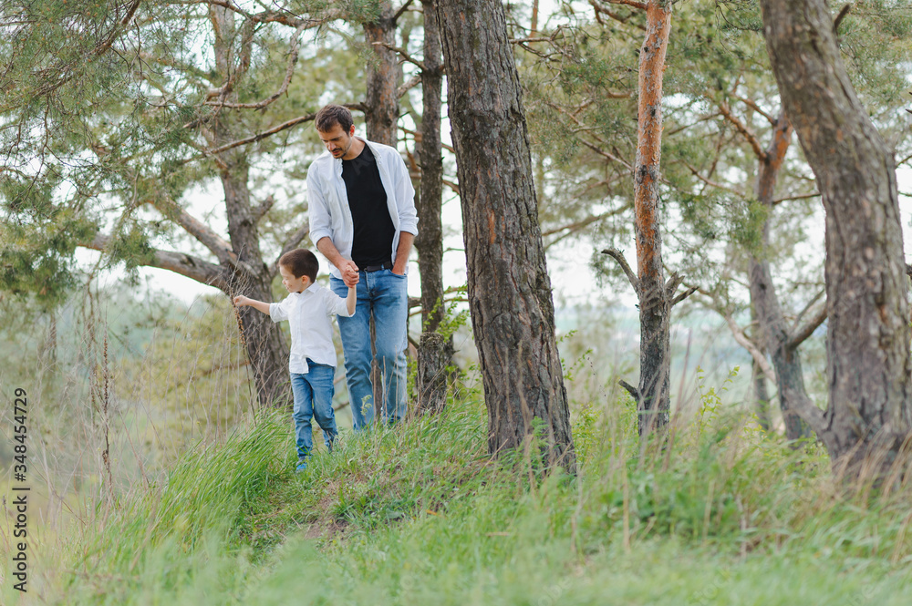 Happy father and son sitting in the park. Smiling young man spending time together with his son. Happy father and son sitting in the park. Smiling young man spending time together with his son.