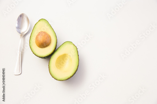 Halved avocado fruit with seed and spoon. Top view. Isolated objects on white background. Fresh food or healthy diet concept