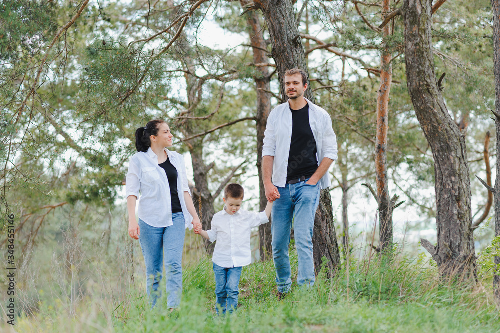 Mom, dad and son walk in the green grass. Happy young family spending time together, running outside, go in nature, on vacation, outdoors. The concept of family holiday.