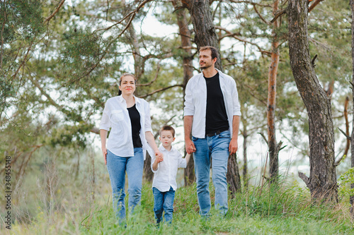 Mom, dad and son walk in the green grass. Happy young family spending time together, running outside, go in nature, on vacation, outdoors. The concept of family holiday.