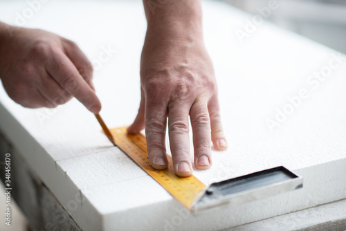 Styrofoam, seiling mounting. A man cuts foam. Warming. Repair in the house. DIY repair. Work with polystyrene foam, insulation of walls and ceiling. Male hands with tools closeup